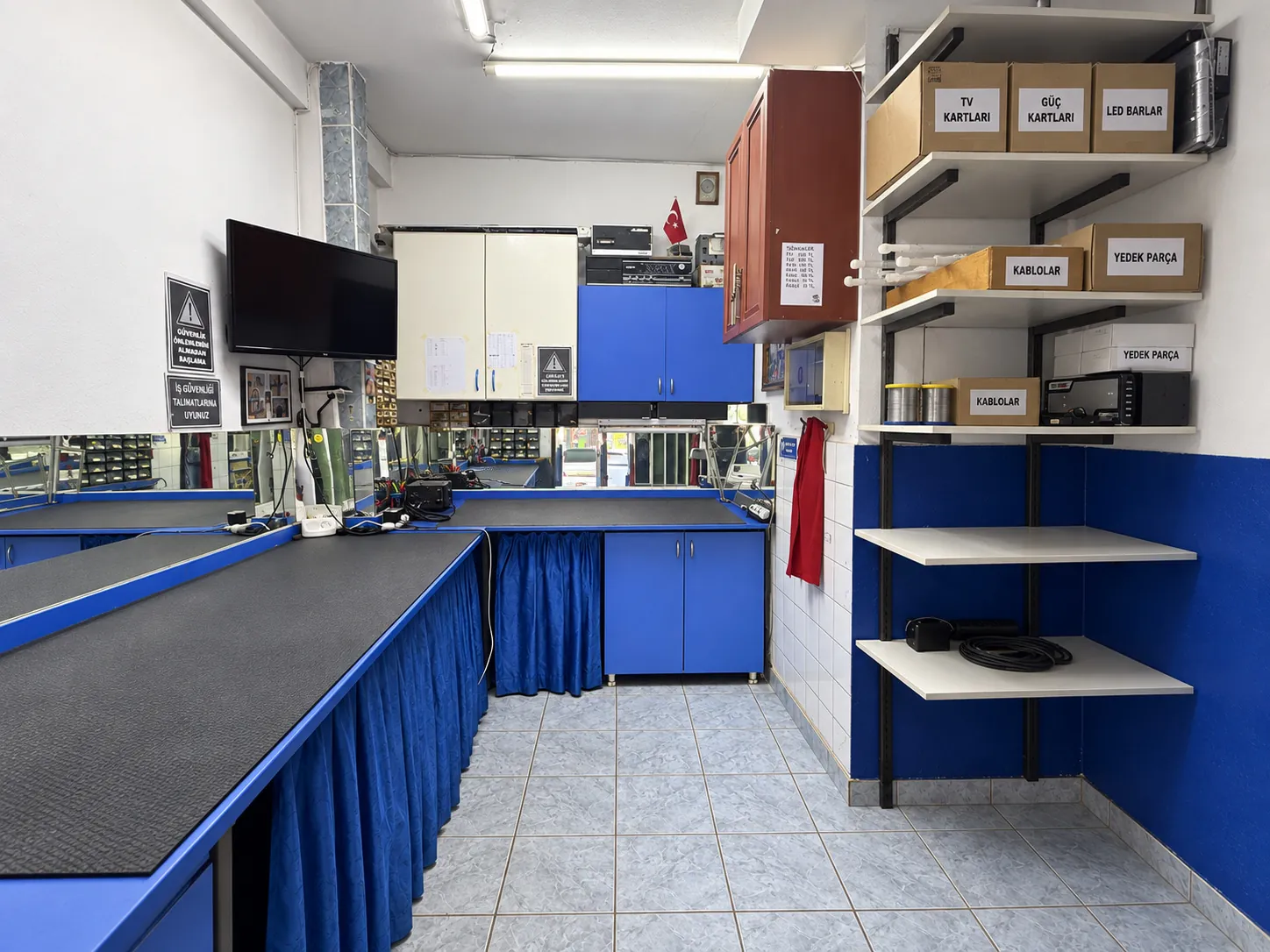 Sistem Elektronik atölyesinde mavi onarım tezgâhları ve parça rafları